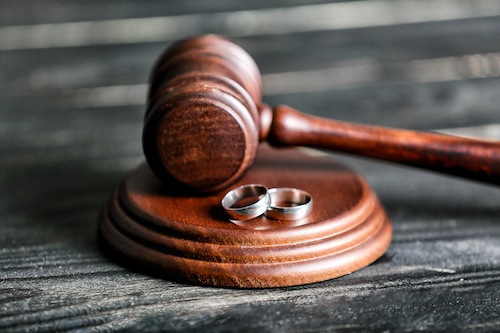 Wedding rings placed near a judge’s gavel represent the end of a marriage relationship after a couple understands the grounds for annulment