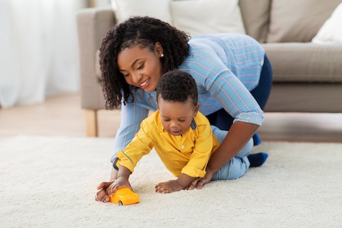 A mother and child playing on the floor after she’s received child support back pay in Texas