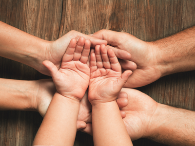 Visual of child’s hands with parents hands supporting underneath after learning how much child support can be taken from a settlement in Texas