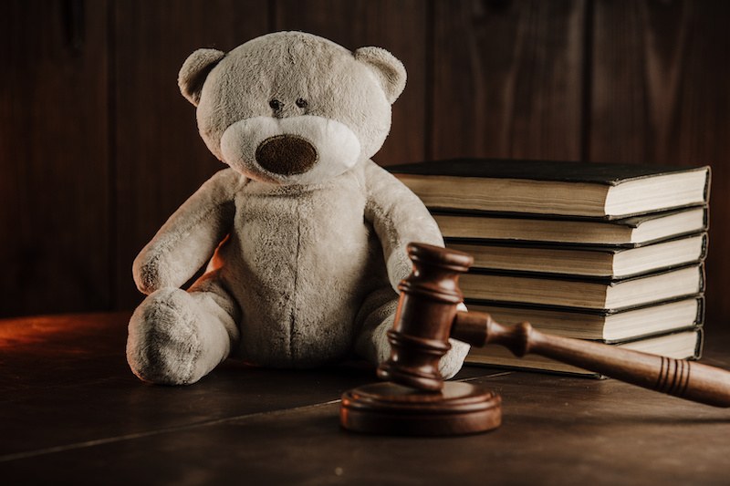 Adoption lawyer image with a gavel and teddy bear sitting on a desk