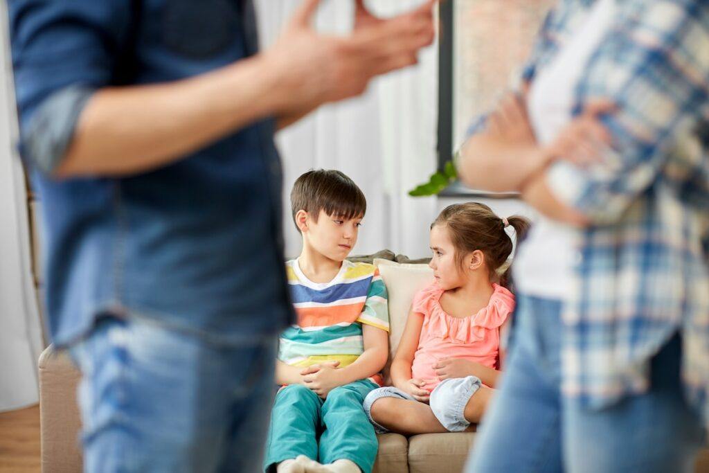 Married couple considering divorce while children sit concerned in the background